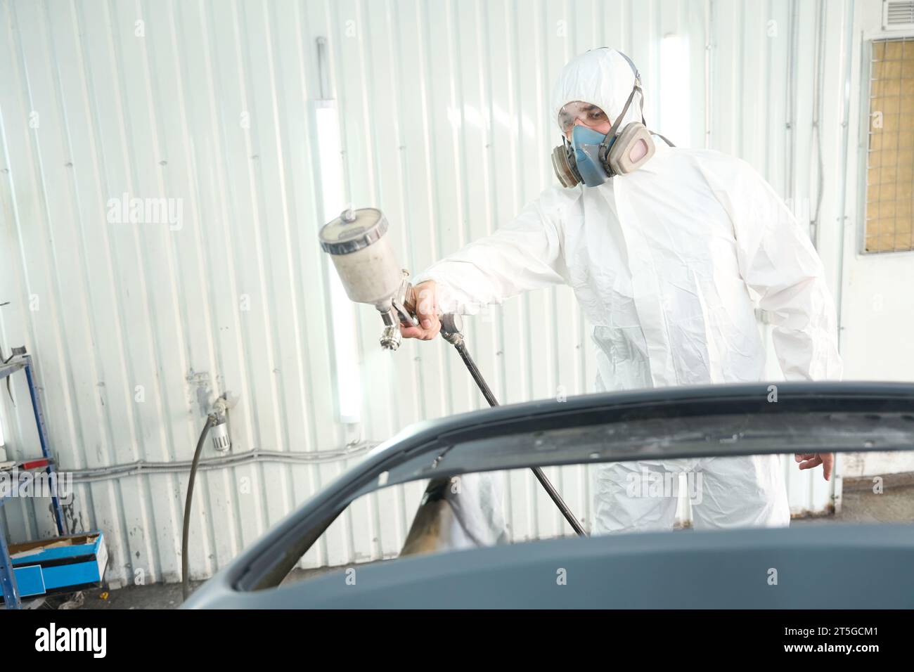 Skilled auto repair shop worker is painting motor vehicle body panel Stock Photo