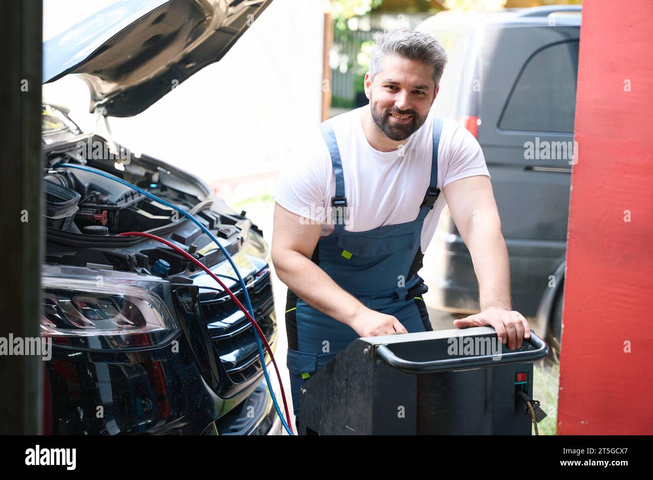 Cheerful auto mechanic checking customer vehicle AC Stock Photo