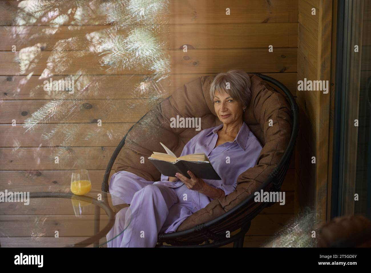 Elegant woman sits in a cozy chair on the terrace Stock Photo - Alamy