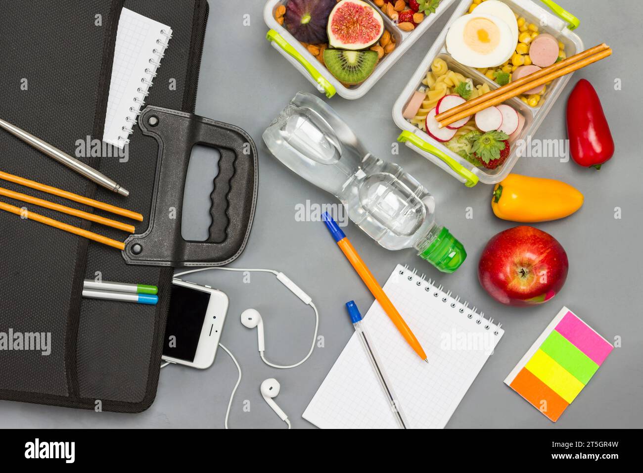 Black briefcase with phone and headphones. Bottle of water, notebooks