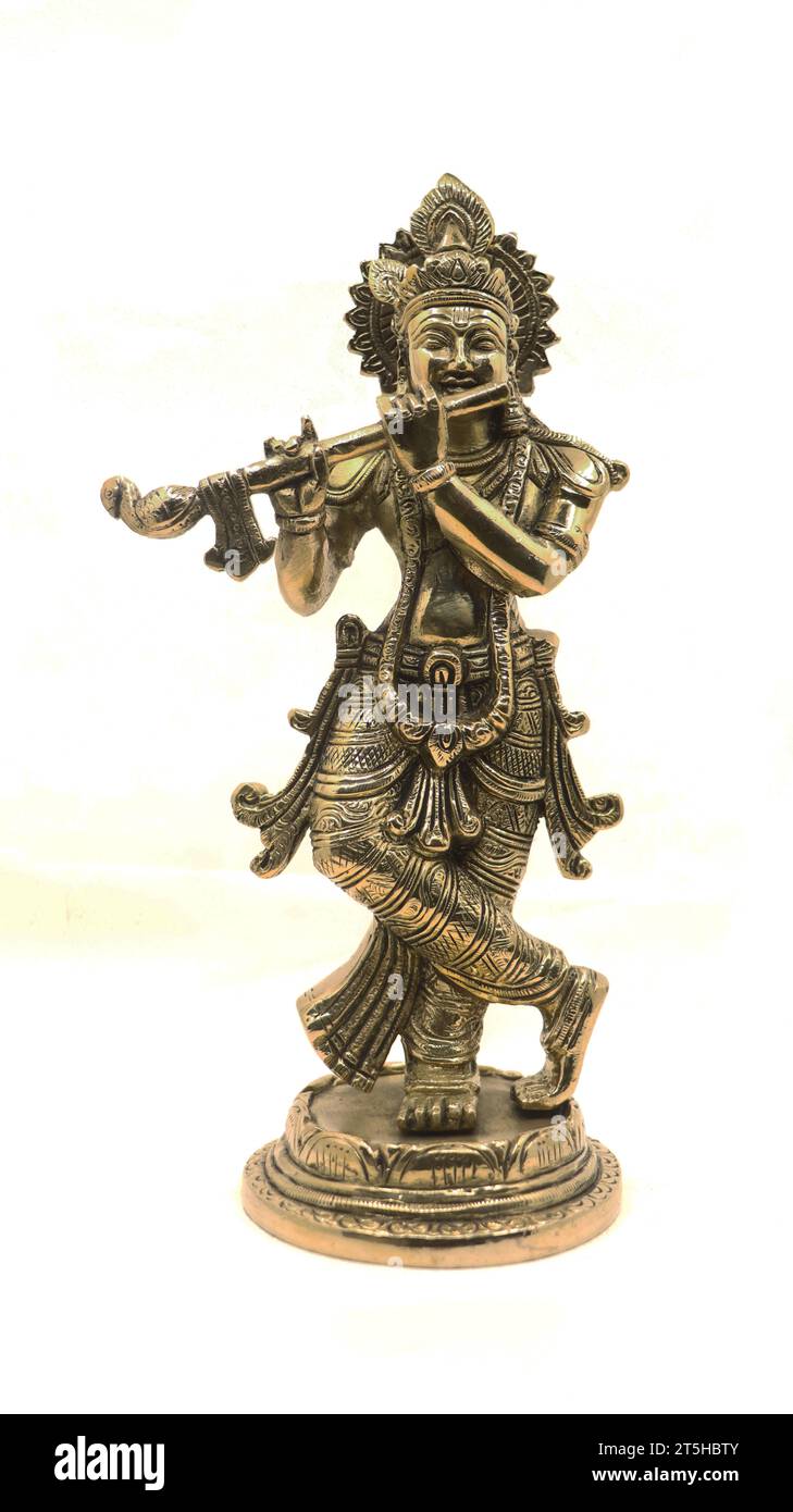 lord krishna playing flute music, an avatar of vishnu god of hindu religion, shiny bronze statue with a crown and ornamental details isolated Stock Photo