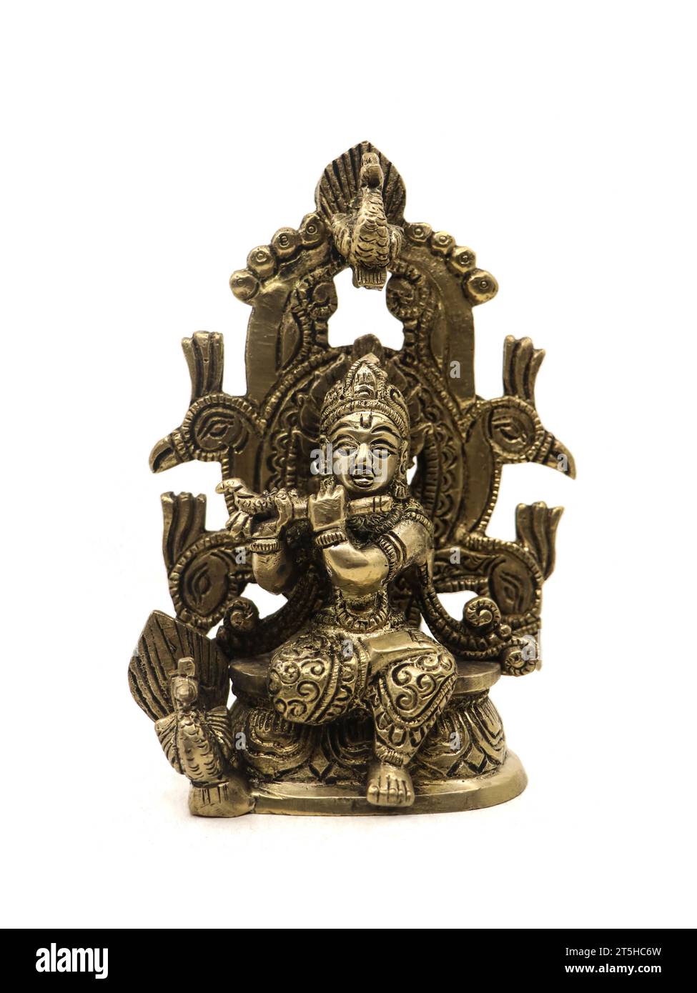 decorative bronze idol of hindu god lord krishna with a flute sitting a on peacock throne isolated in a white background Stock Photo