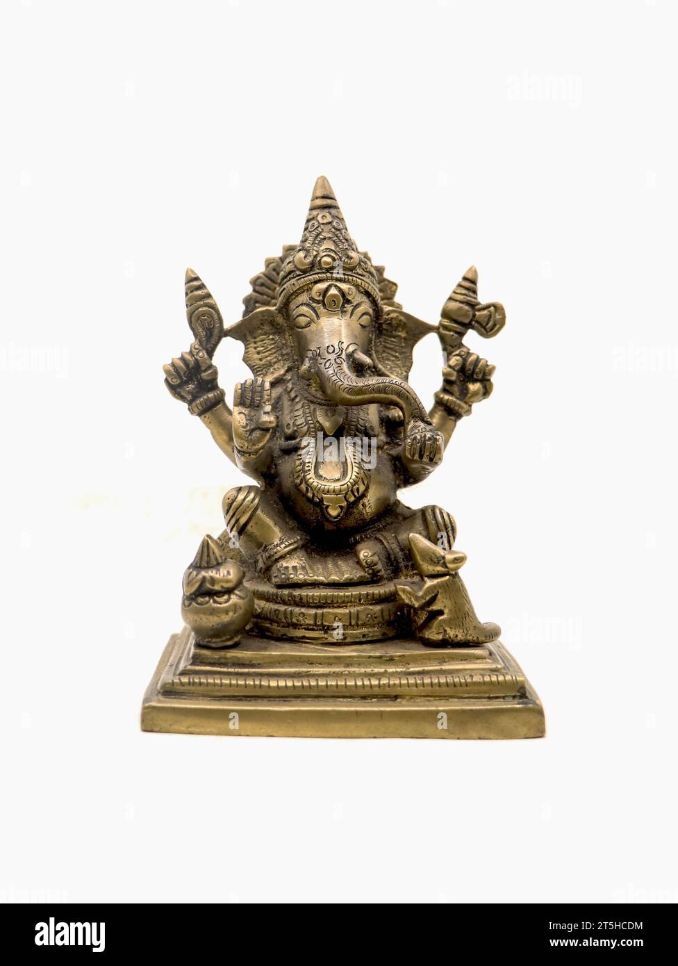 front view of sitting ganesh with four hands, brass statue with intricate details and decorative carvings isolated in a white background Stock Photo