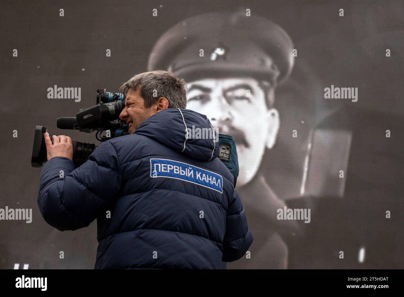 Moscow, Russia. 5th of November, 2023. A cameraman of the Channel One Russia shoots a story against the background of a portrait of Joseph Stalin about an open-air museum in Red Square in Moscow; the museum opened to mark the 82th anniversary of the historical 7 November 1941 Red Square Parade when Red Army troops were leaving for the front lines of World War II to defend Moscow from the Nazi forces.The patch reads 'The Channel One' Stock Photo