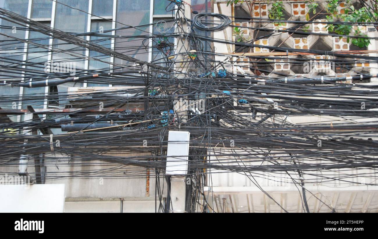 A huge pile of tangled wires hanging on a lamp post. Stock Photo