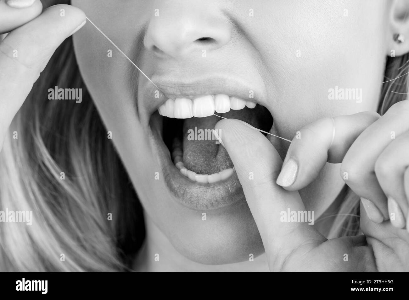 Teeth Flossing. Woman use dental floss white healthy teeth. Dental flush - woman flossing teeth. Black and white Stock Photo