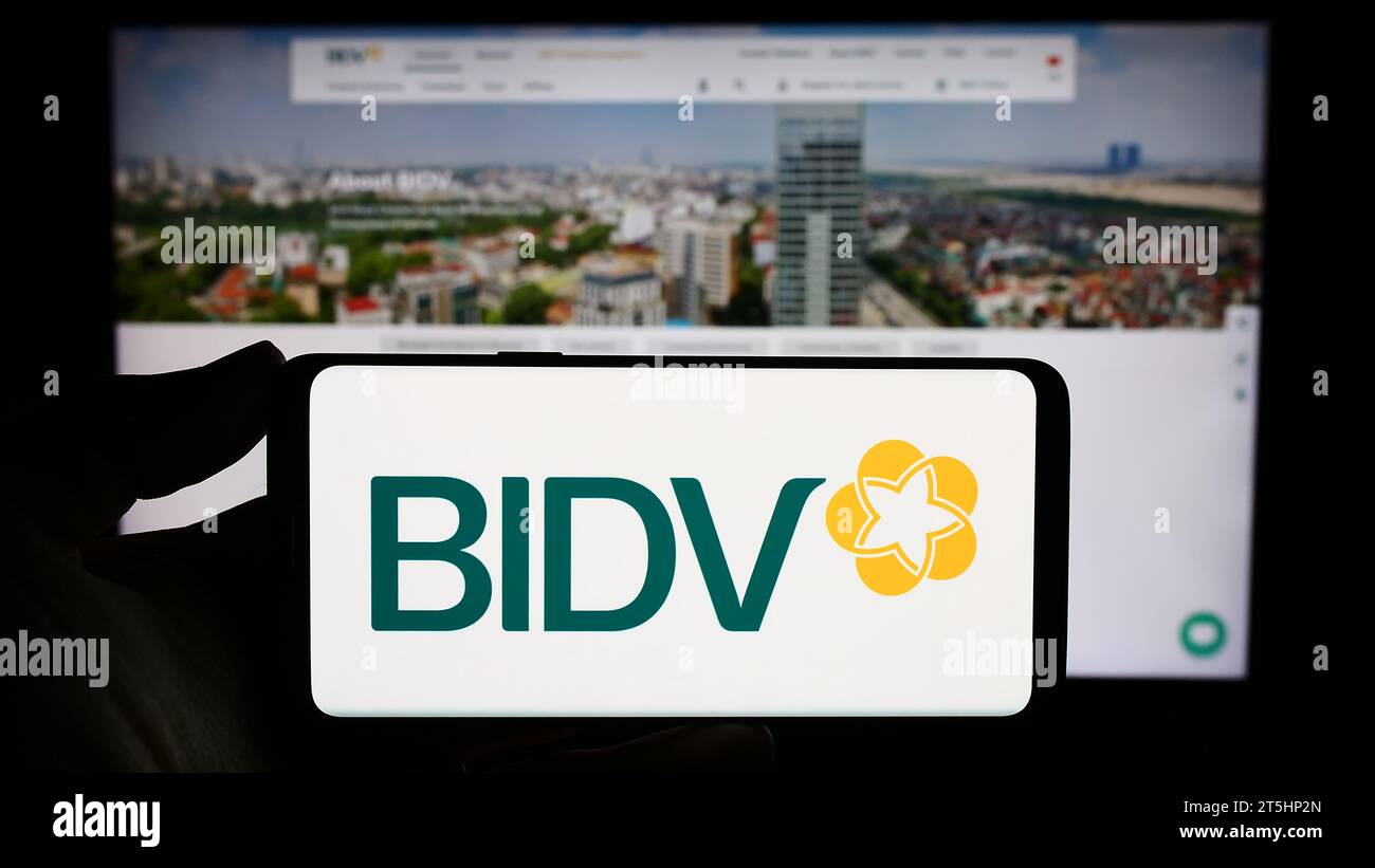 Person holding smartphone with logo of commercial bank for investment