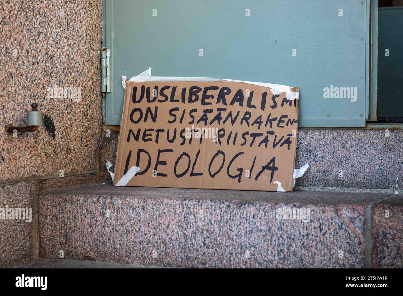 Uusliberalismi on sisäänrakennetusti riistävä ideologia. Cardboard sign on Helsinki University main campus building steps in Helsinki, Finland. Stock Photo