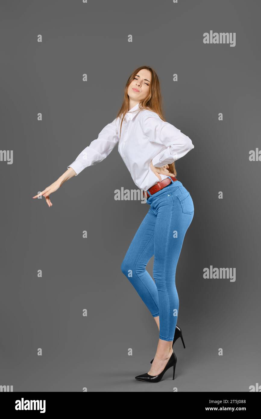 Naughty woman in white shirt and blue jeans pointing at something with her finger Stock Photo