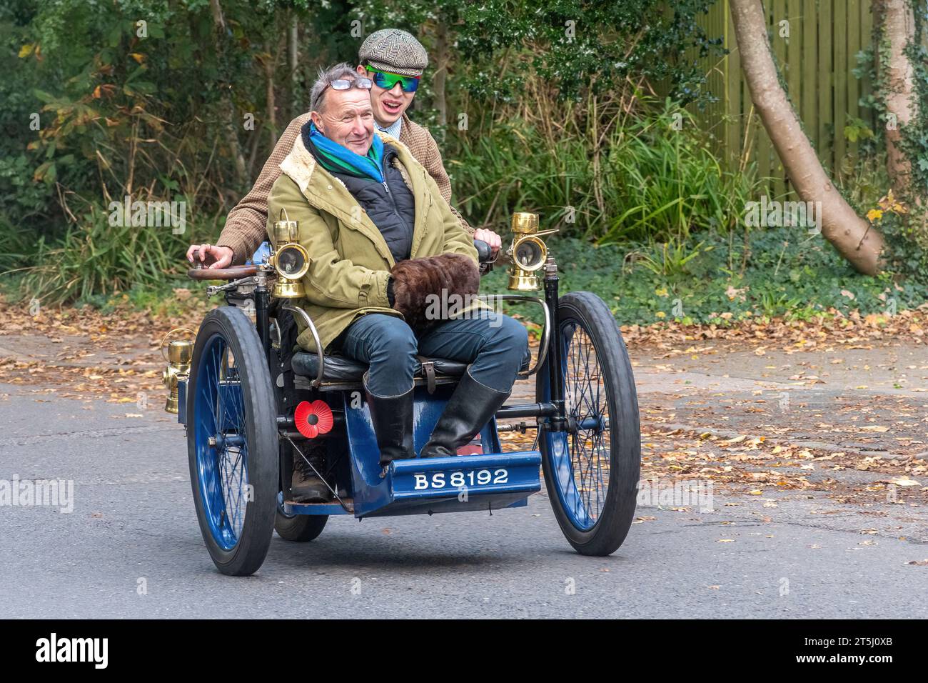 5th November 2023. Participants in the London to Brighton Veteran Car Run 2023 driving through West Sussex, England, UK. The route of the popular annual event runs for 60 miles. Pictured: two men in a blue 1900 Leon Bollee three wheel vehicle (tricar). Stock Photo