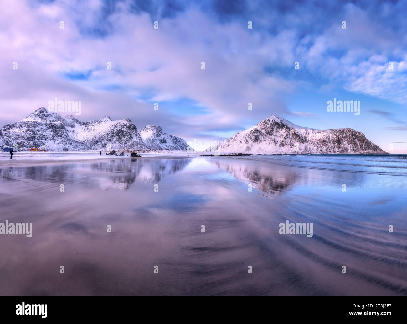 Sandy beach with blue sea reflected in water and rocks in snow Stock ...