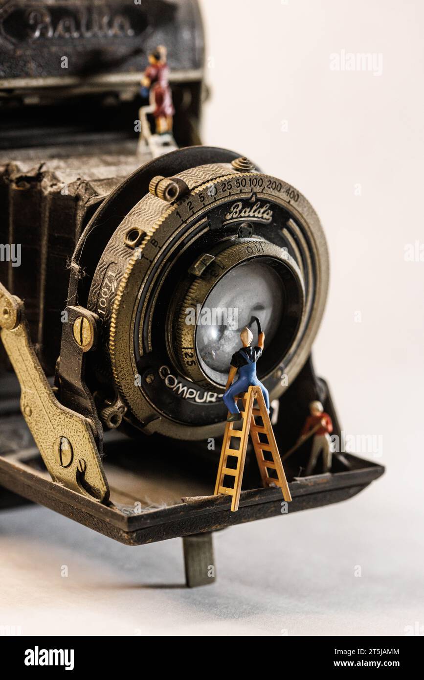 Miniature Figurines Cleaning an Old Dusty Vintage Camera Stock Photo