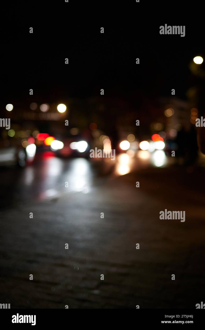 Out of focus view of cars passing at street level at night Stock Photo