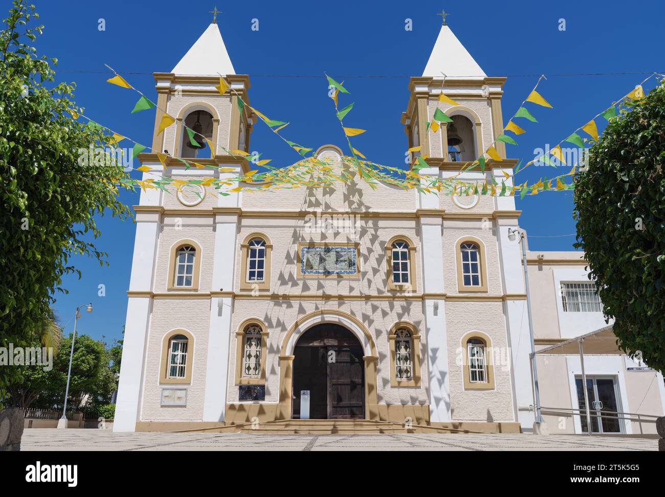 The Mision de San Jose Church in San Jose del Cabo, Mexico. The building is decorated with strings of green and yellow triangular flags. Stock Photo