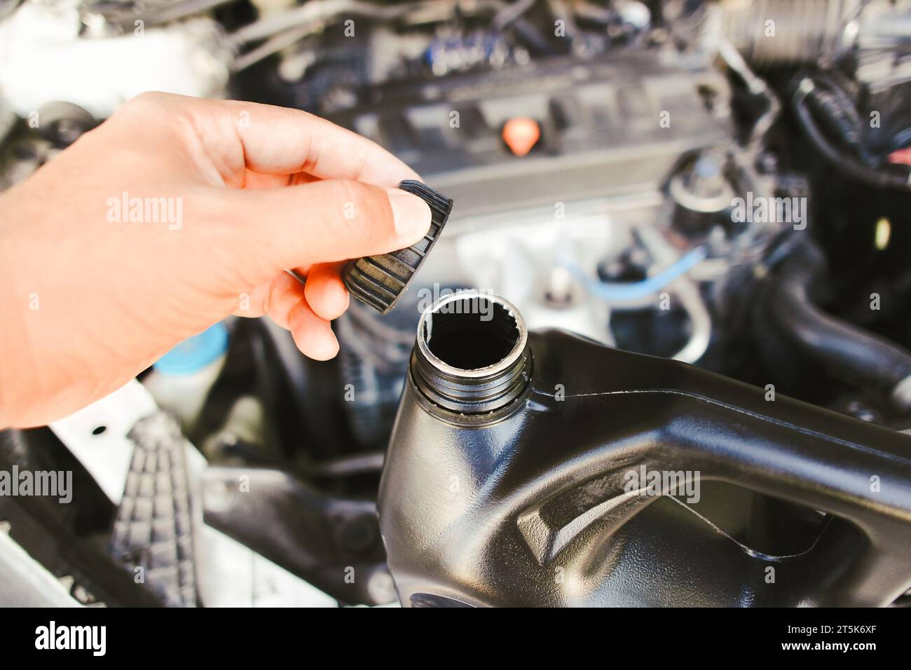 The hand of a car mechanic opens the engine oil cap to inspect before