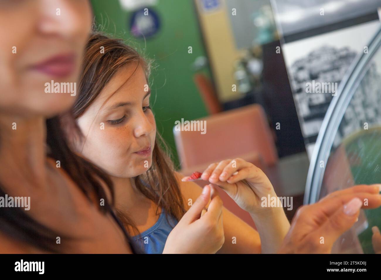 Cute Young Girl Sampling a Taste of Gelato with Her Mother at the Ice Cream Shop. Stock Photo