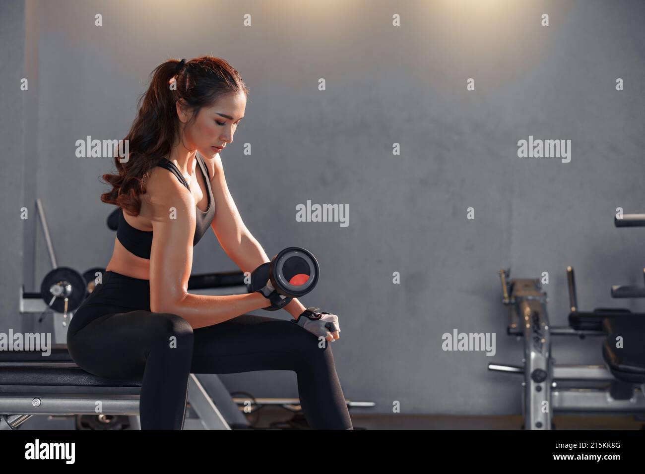 Fitness asian woman doing exercise and lifting dumbbells weights at sport gym. Stock Photo