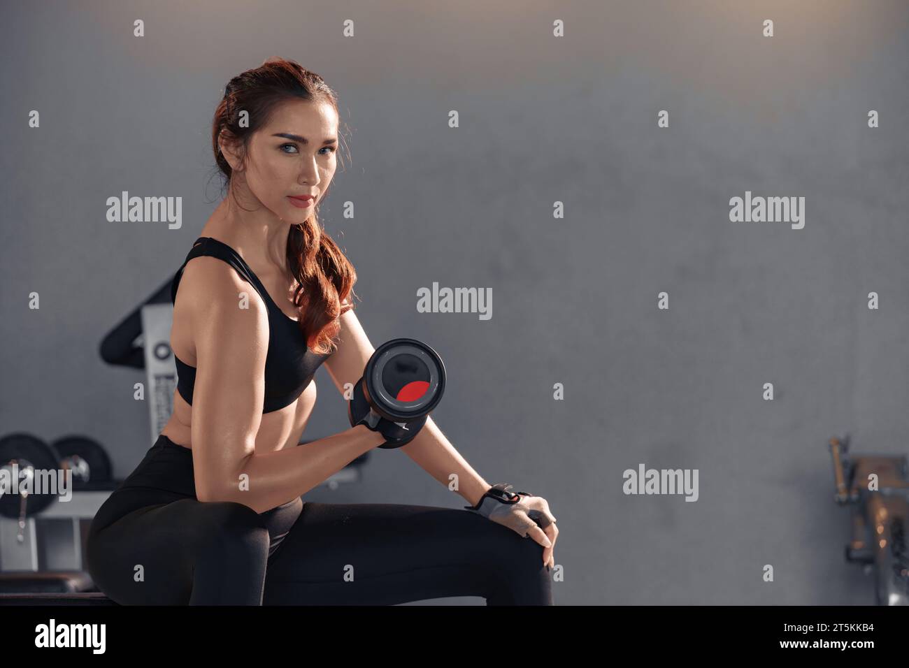 Fitness asian woman doing exercise and lifting dumbbells weights at sport gym. Stock Photo