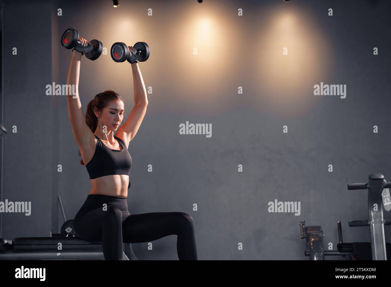 A woman wearing tight shorts and a sports crop top holding weights