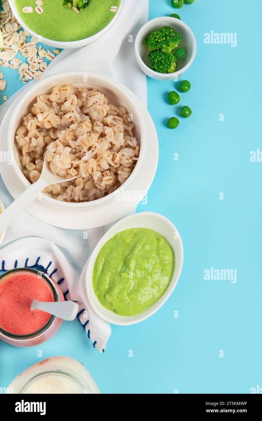 Bowls with healthy baby food on blue background. Top view, copy space. Stock Photo