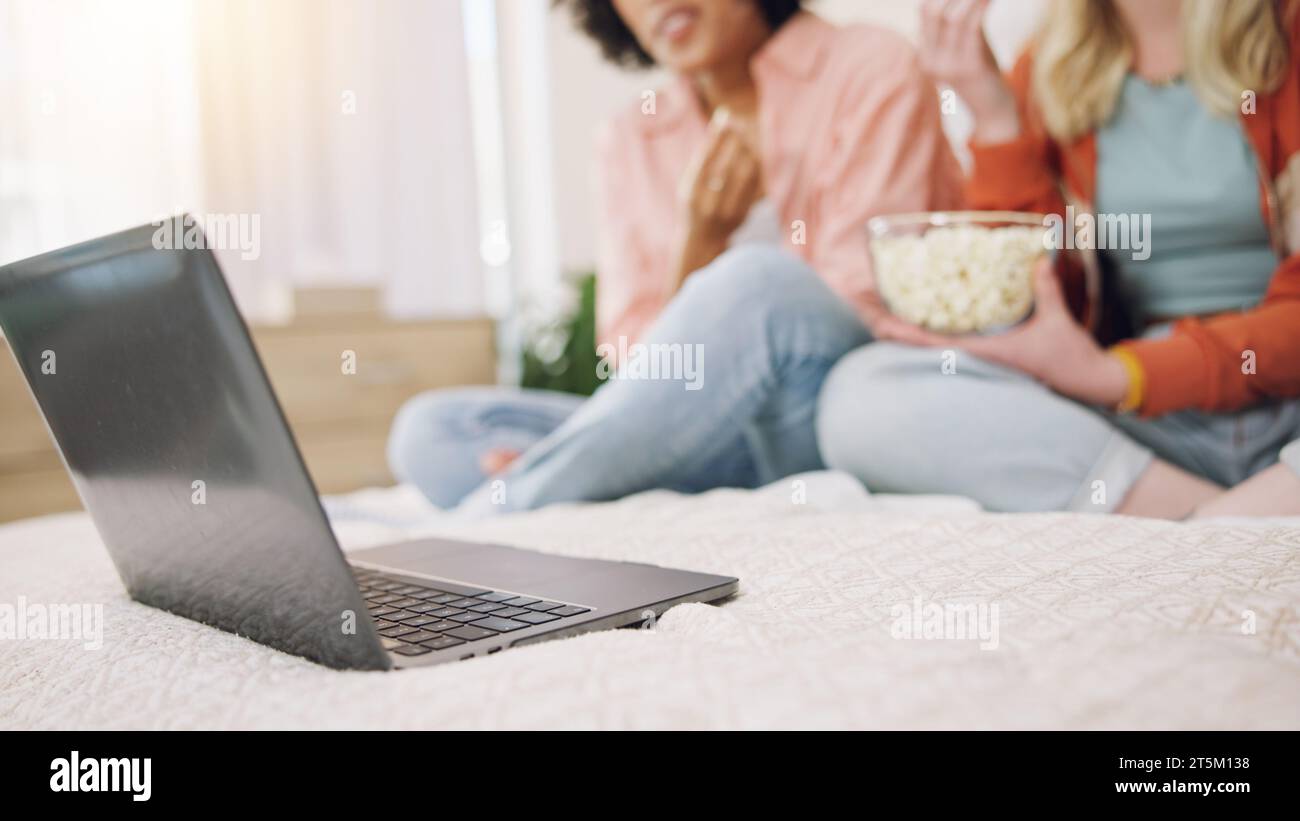 Laptop, movie and women friends on a bed with popcorn for comedy, program or film in their home. Online, video and ladies in a bedroom with snack for Stock Photo
