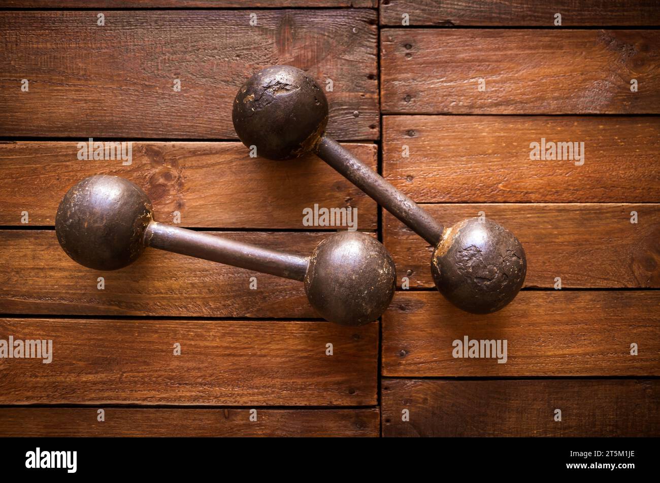 Old rusty dumbbells on rustic wood board background texture Stock Photo