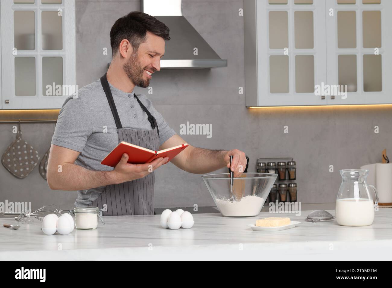 Happy man cooking by recipe book in kitchen Stock Photo