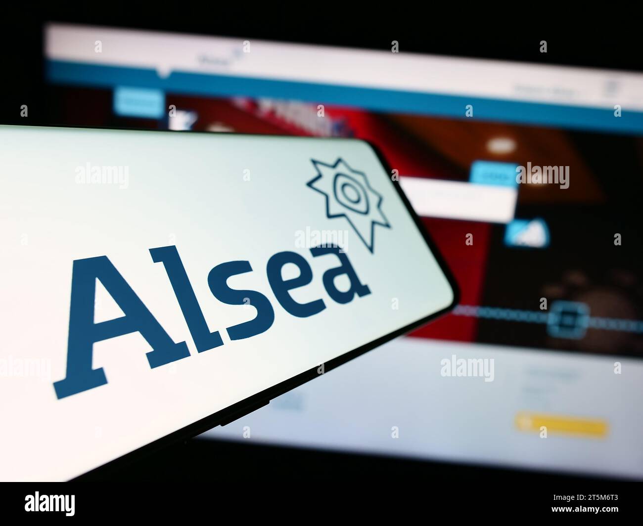 Mobile phone with logo of Mexican restaurant company Alsea SAB de CV in front of business website. Focus on center-left of phone display. Stock Photo