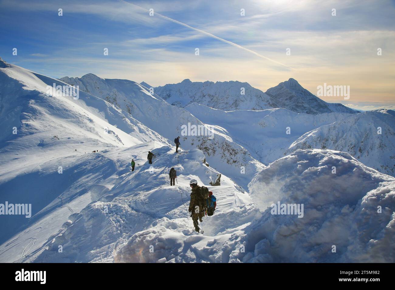 Tied climbers climbing mountain with snow field tied with a rope with ice axes and helmets Stock Photo