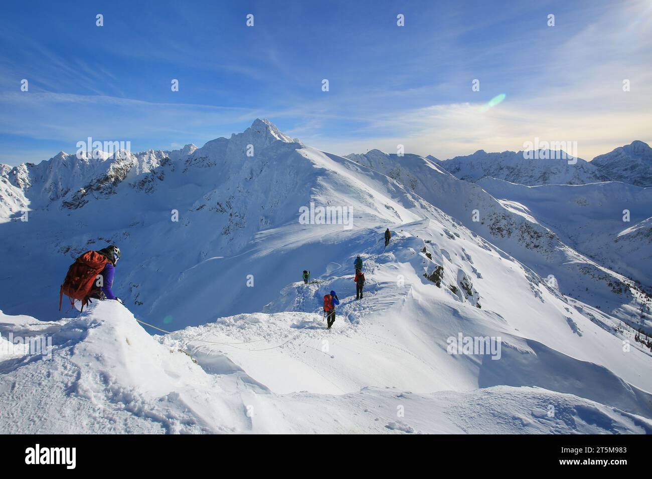 Tied climbers climbing mountain with snow field tied with a rope with ice axes and helmets Stock Photo
