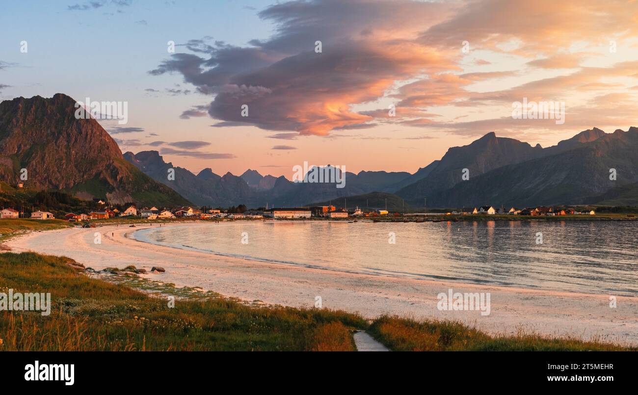 Sunset over a beach in Lofoten, Rambergstranda, in the summer, near Ramberg. Mostly clear sky, high mountains and distant fjord. Pink clouds. Stock Photo