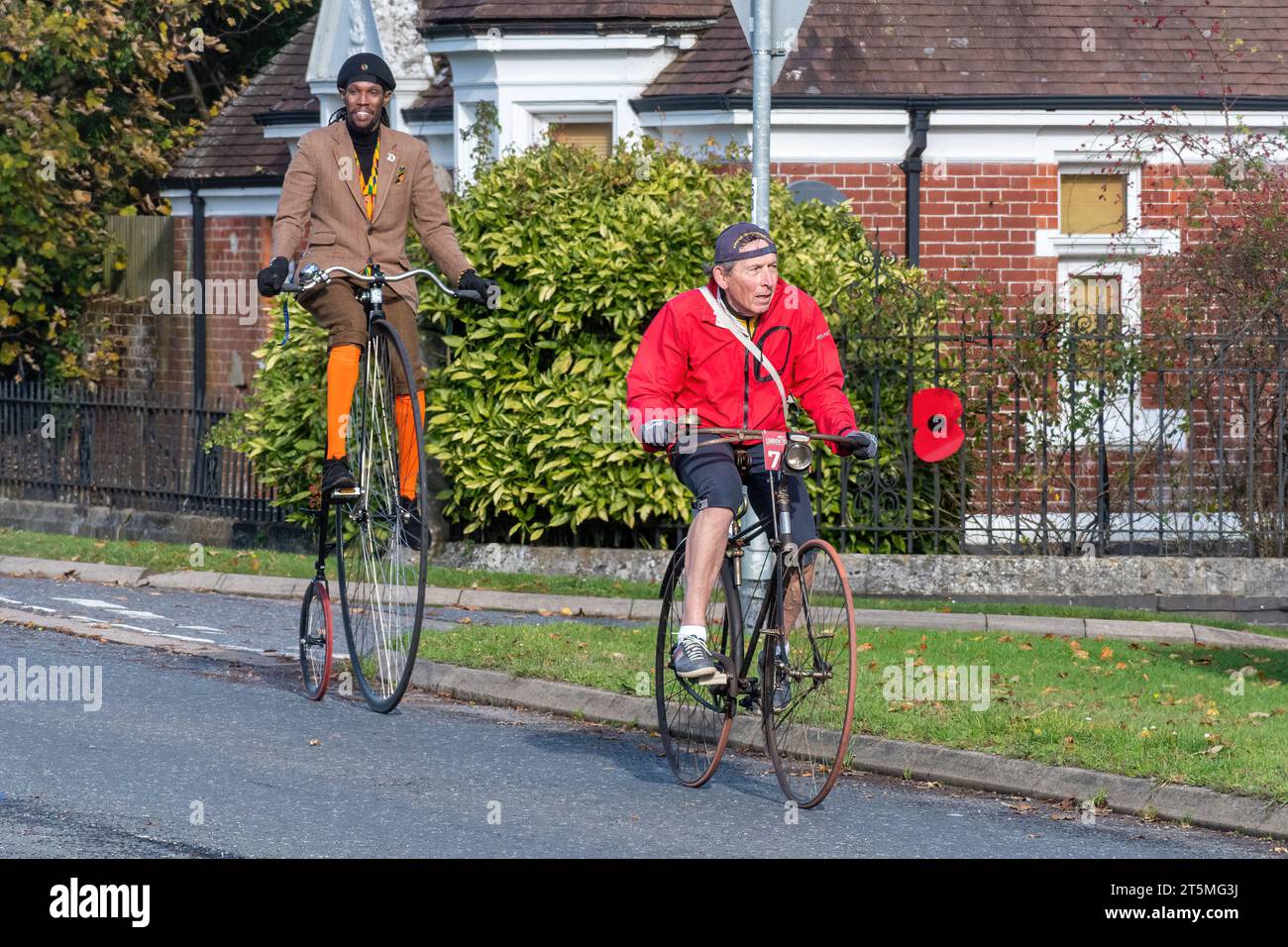 5th November 2023. Participants in the London to Brighton Veteran Car Run 2023 driving through West Sussex, England, UK. The route of the popular annual event runs for 60 miles. Two men riding old bicycles, one of them on a penny farthing. Stock Photo