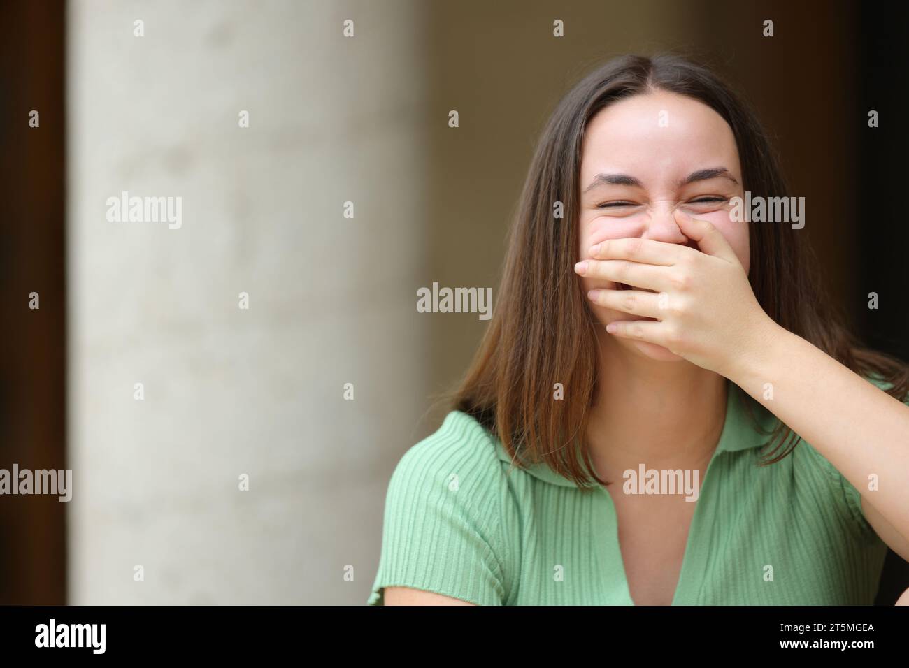 Happy woman laughing covering mouth looks at you in the street Stock Photo