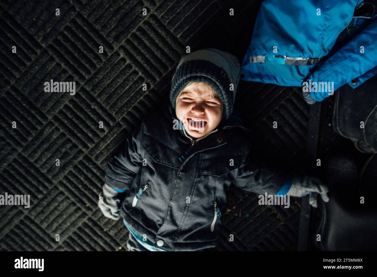 Overhead view of little boy crying and throwing tantrum on floor Stock Photo