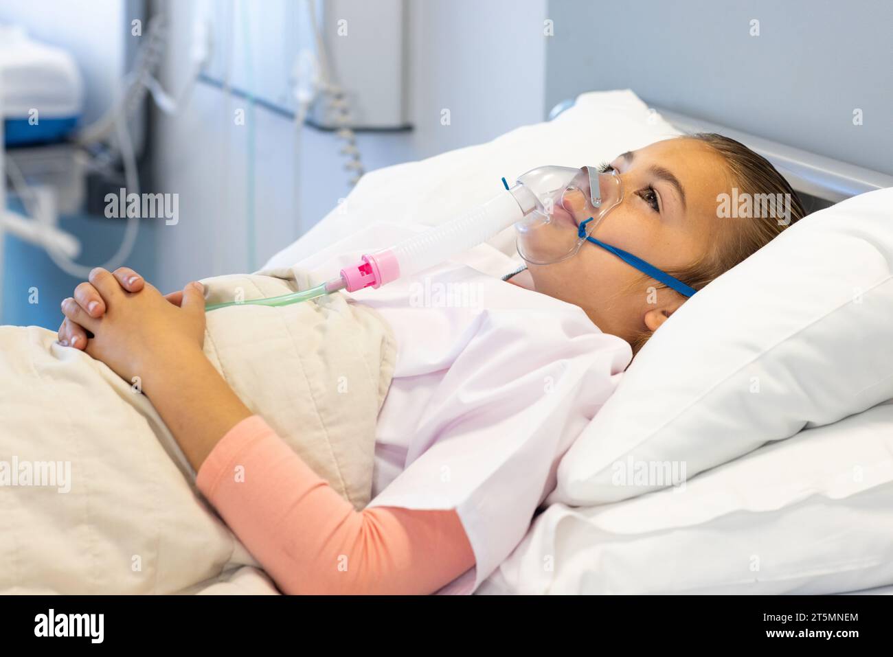Caucasian girl patient in oxygen mask lying in hospital bed Stock Photo