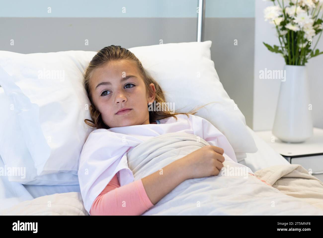 Sick caucasian girl patient lying in hospital bed looking away Stock Photo