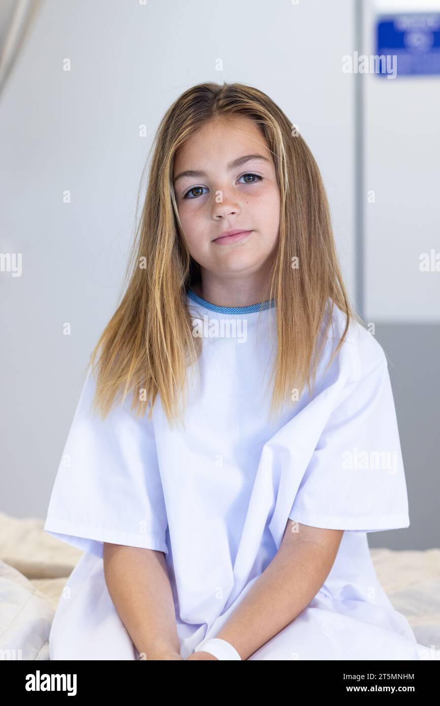 Portrait of smiling caucasian girl patient sitting in hospital ward in