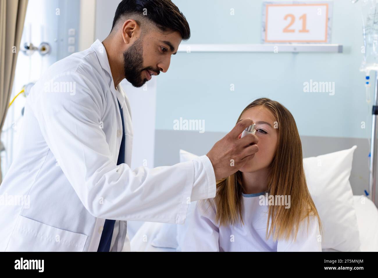Focused diverse male doctor helping girl patient use asthma inhaler