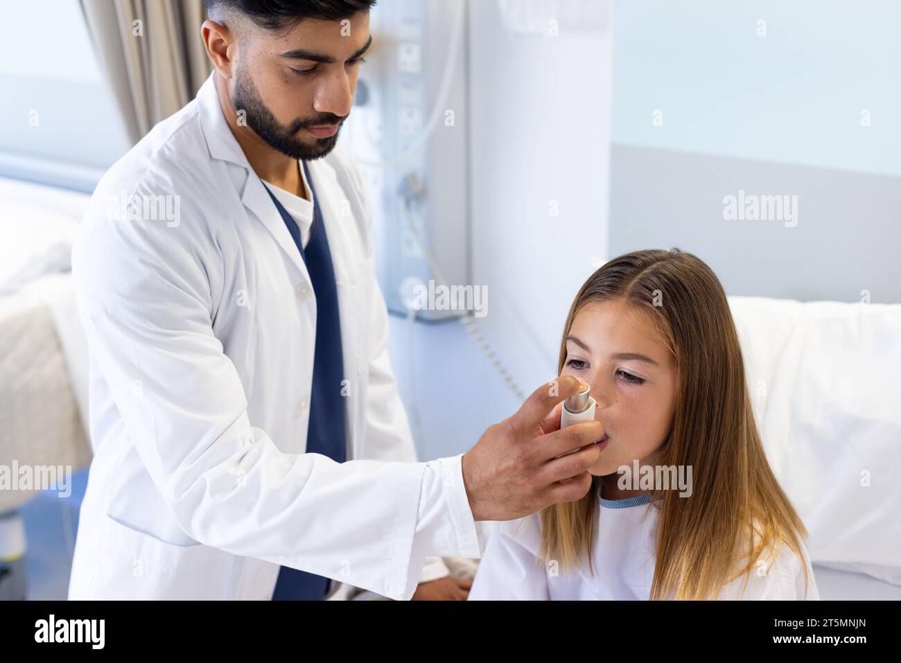 Focused diverse male doctor helping girl patient use asthma inhaler