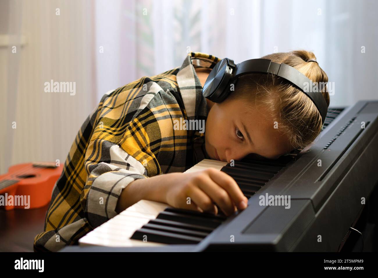 Young musician resting on a piano keyboard with headphones Stock Photo