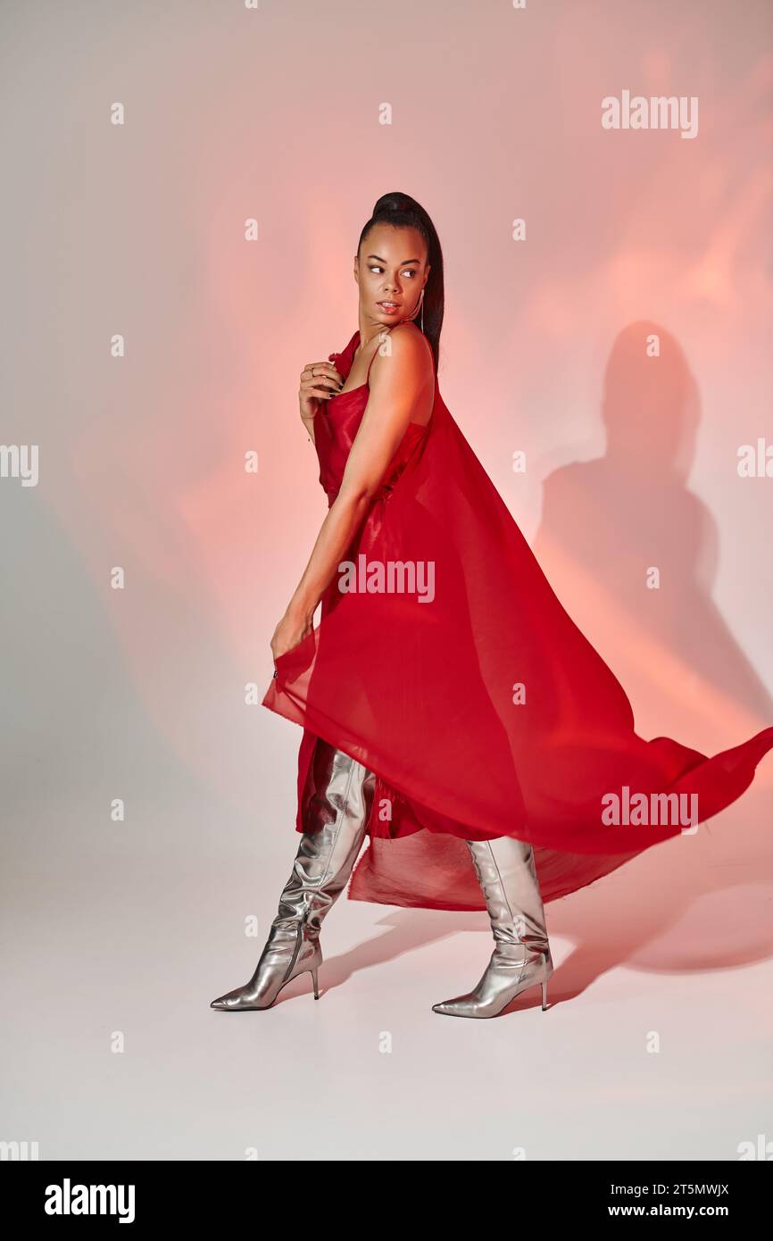 african american woman in red dress and shawl walking in silver boots on  grey with lighting Stock Photo - Alamy