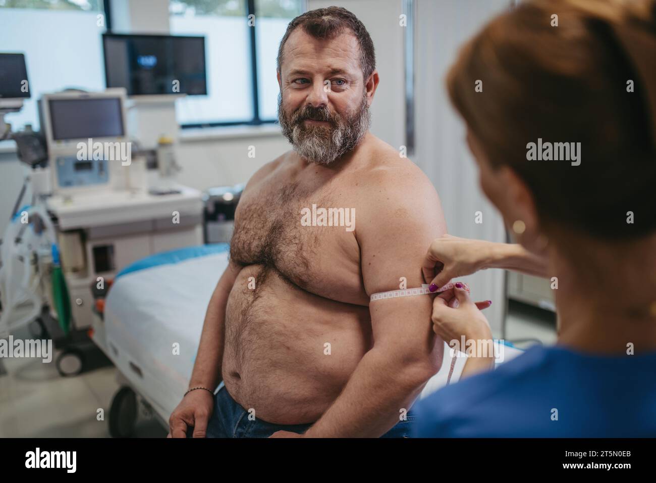 Female doctor measuring arm circumference of overweight patient using