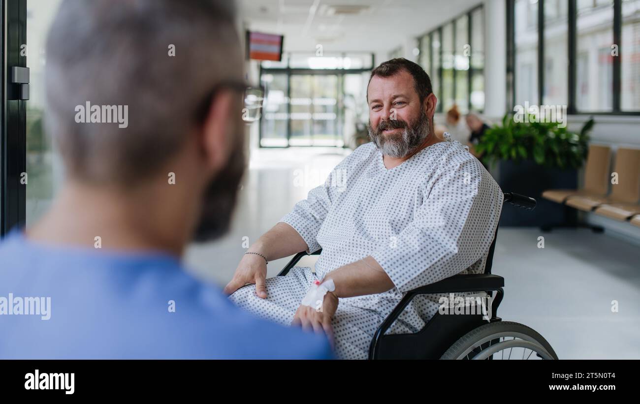 Close up of supportive doctor talking with worried overweight patient in wheelchair. Illnesses