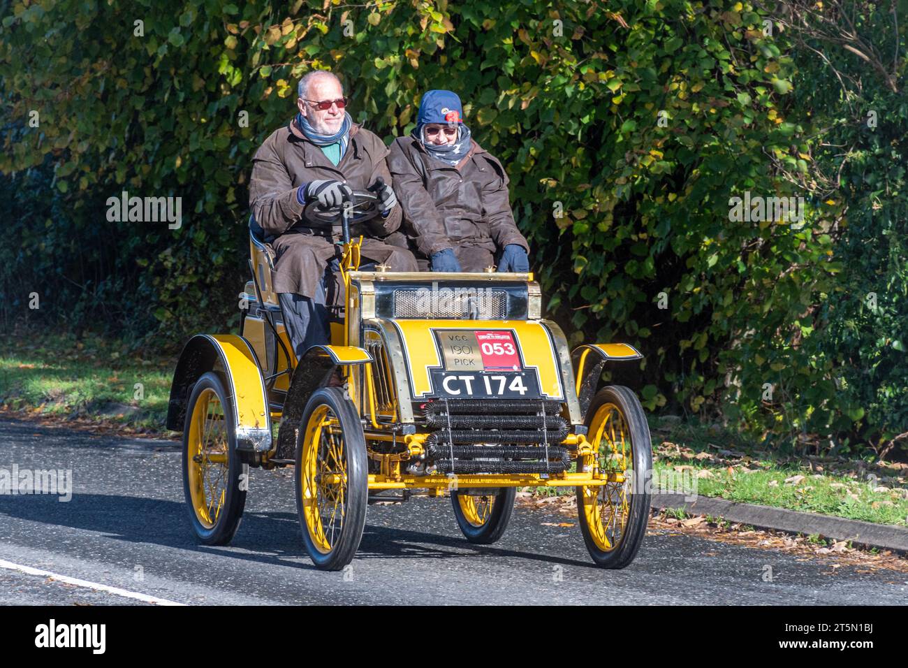 5th November 2023. Participants in the London to Brighton Veteran Car Run 2023 driving through West Sussex, England, UK. The route of the popular annual event is about 60 miles long. Pictured: a yellow 1901 Pick two seater car. Stock Photo