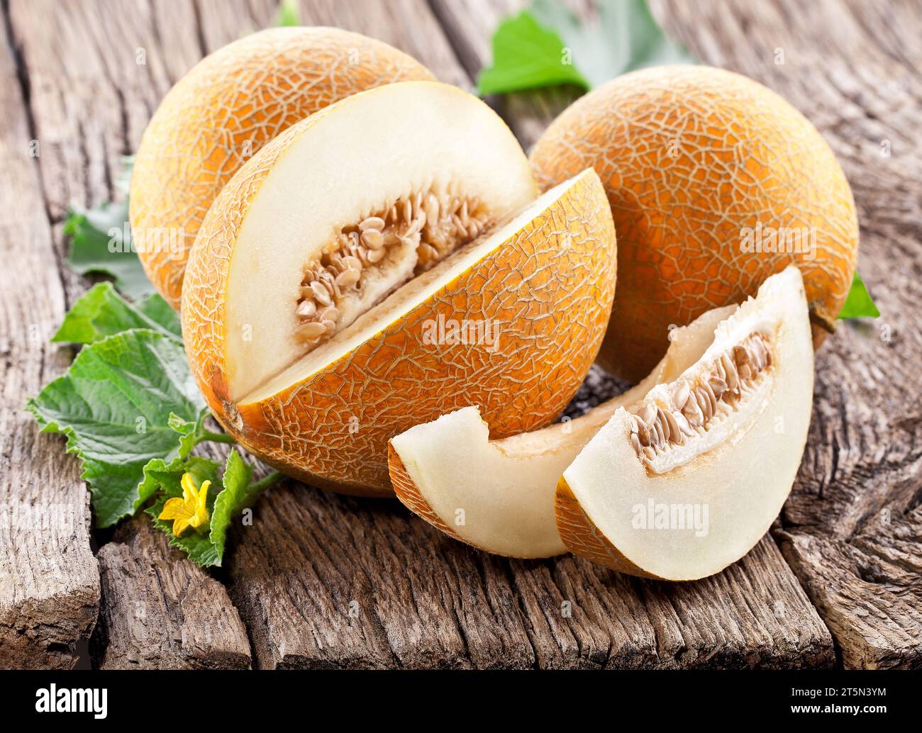 Cantaloupe melon with leaf and melon slice on old wooden table. Stock Photo