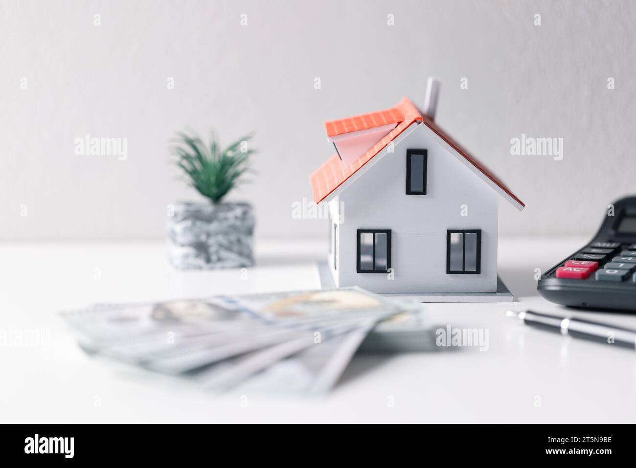 House with money. Concept of finance or refinance real estate. Symbol of house stands against background of us dollars. Property investment. Home mort Stock Photo