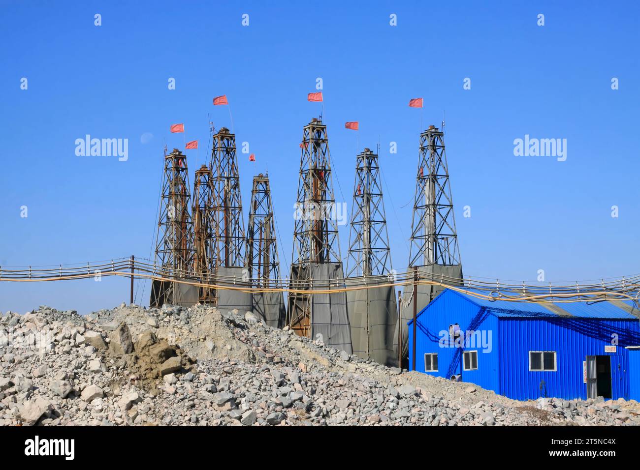 Drilling rig derrick and metal housing under blue sky Stock Photo