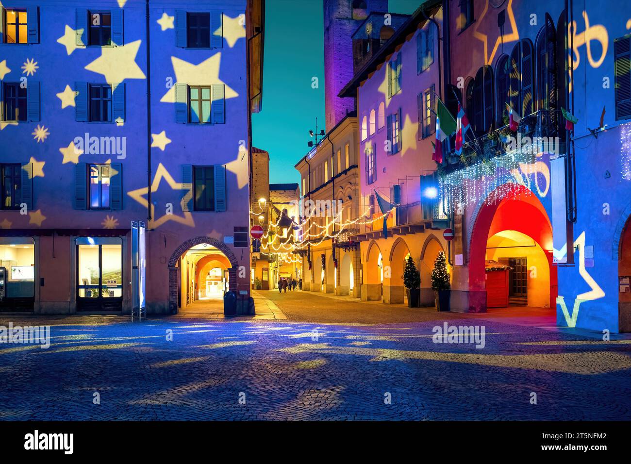 Town square, cobblestone street and old historic buildings illuminated and decorated for Christmas holidays in historic town of Alba, Piedmont, Italy. Stock Photo