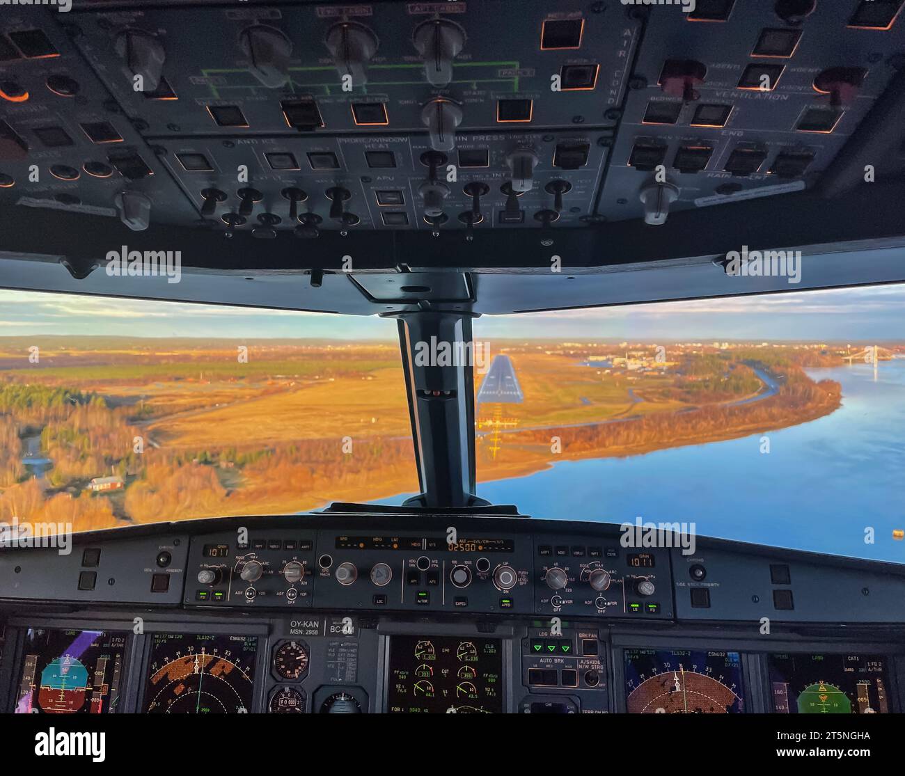 Interior of a jet airplane cockpit on final approach to a runway, at Umeå airport. Clear sky and autumn colors. Stock Photo
