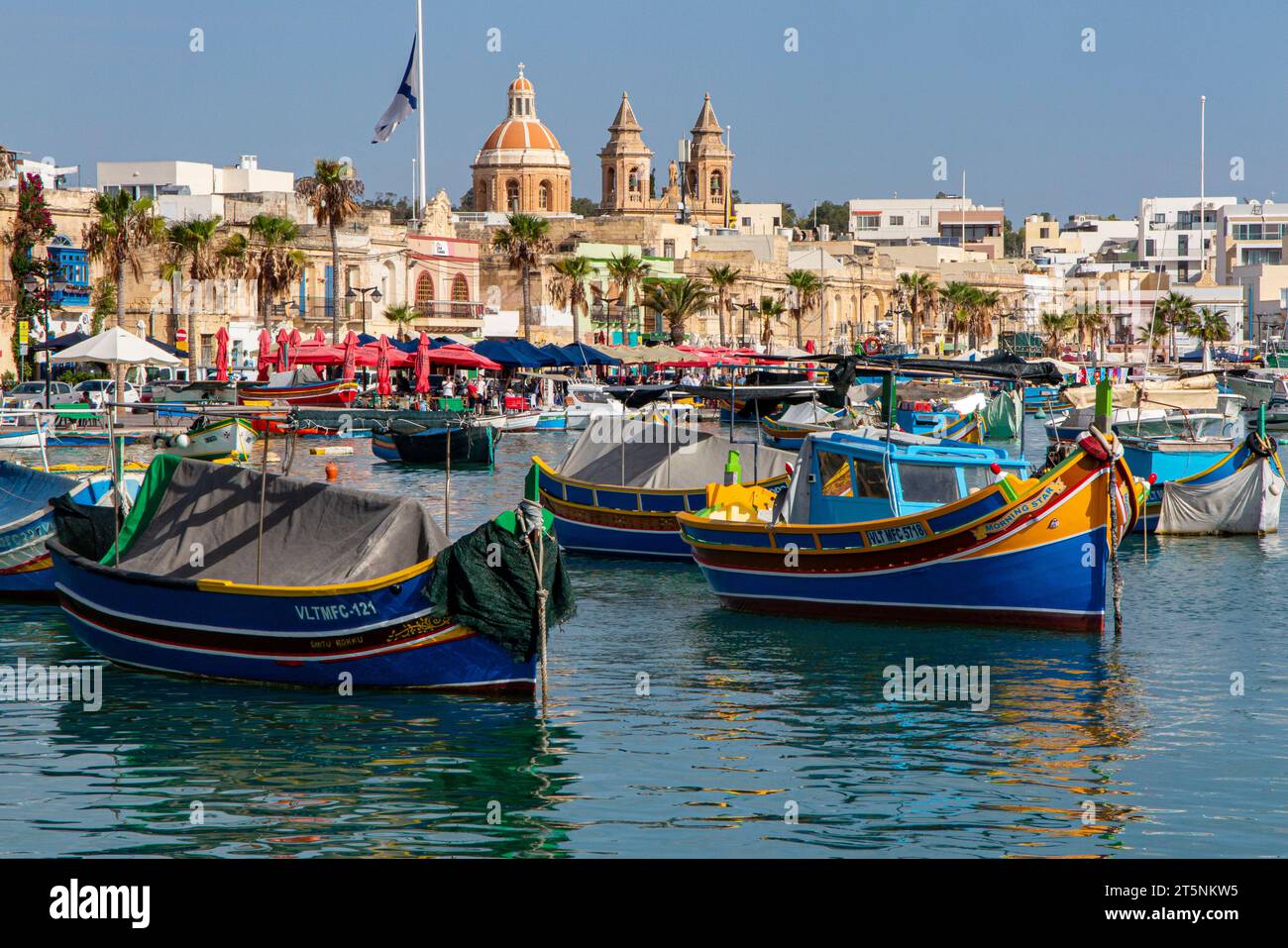 The coloured boats in Marsaxlokk Harbour and Church of our Lady. Malta Stock Photo